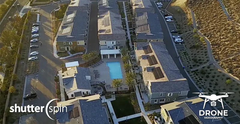 Drone aerial view of a modern subdivision with pool and townhomes, captured by ShutterSpin. Aerial videography highlights community features for real estate listings and enhances property marketing.